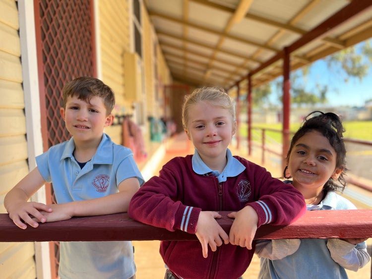 Three infants students standing on verandah