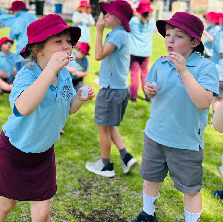 Two students blowing bubbles on the grass