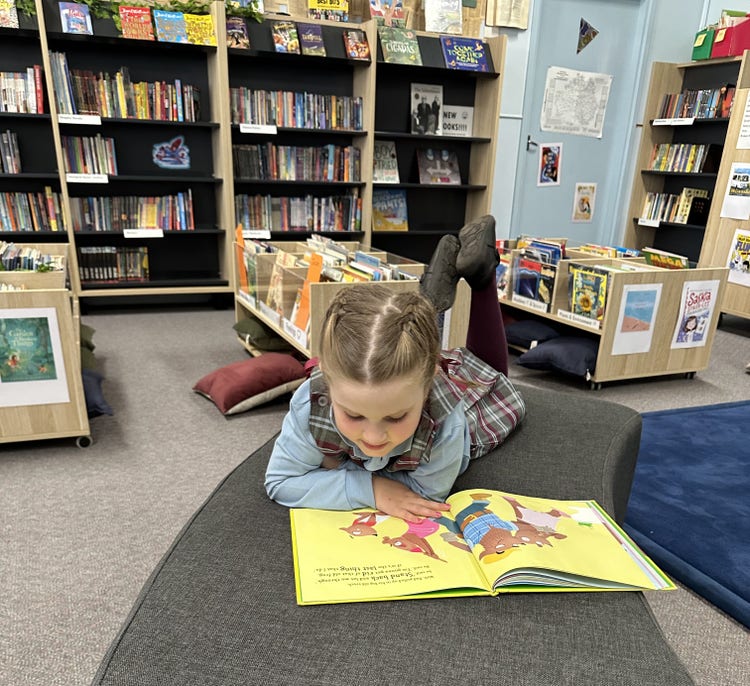 Kinder girl reading in library