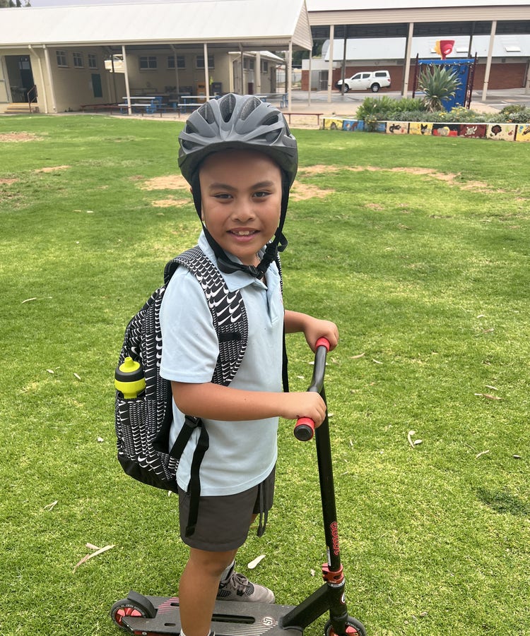 Student riding walking scooter out of school