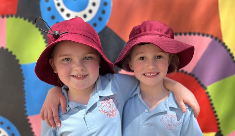 Two girls smiling in front of colourful mural