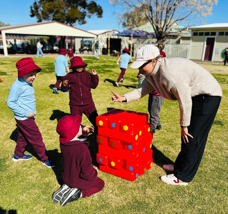 Students and teacher playing jenga outside