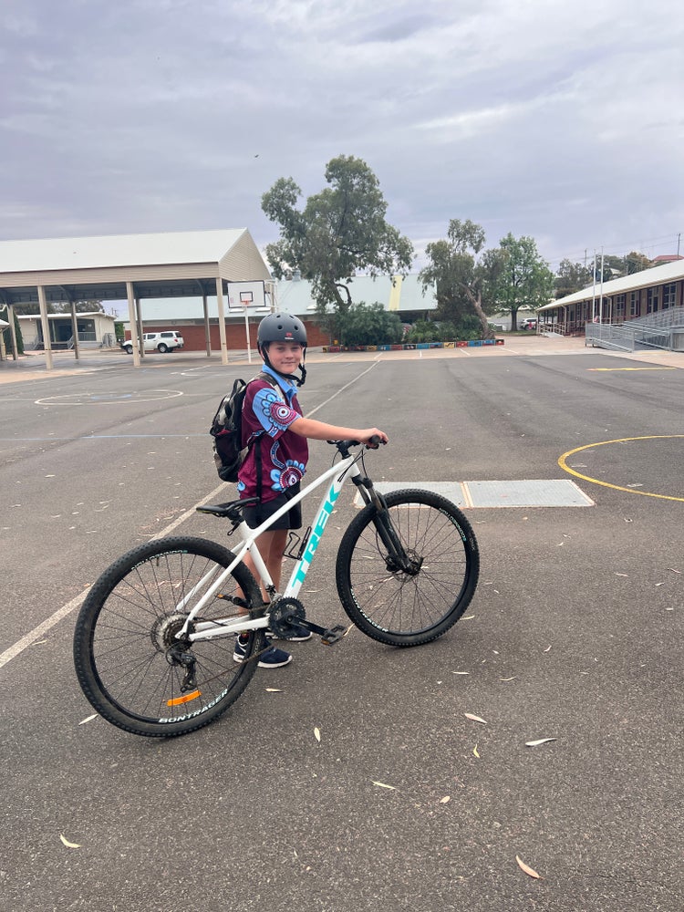 Boy walking bike out of school